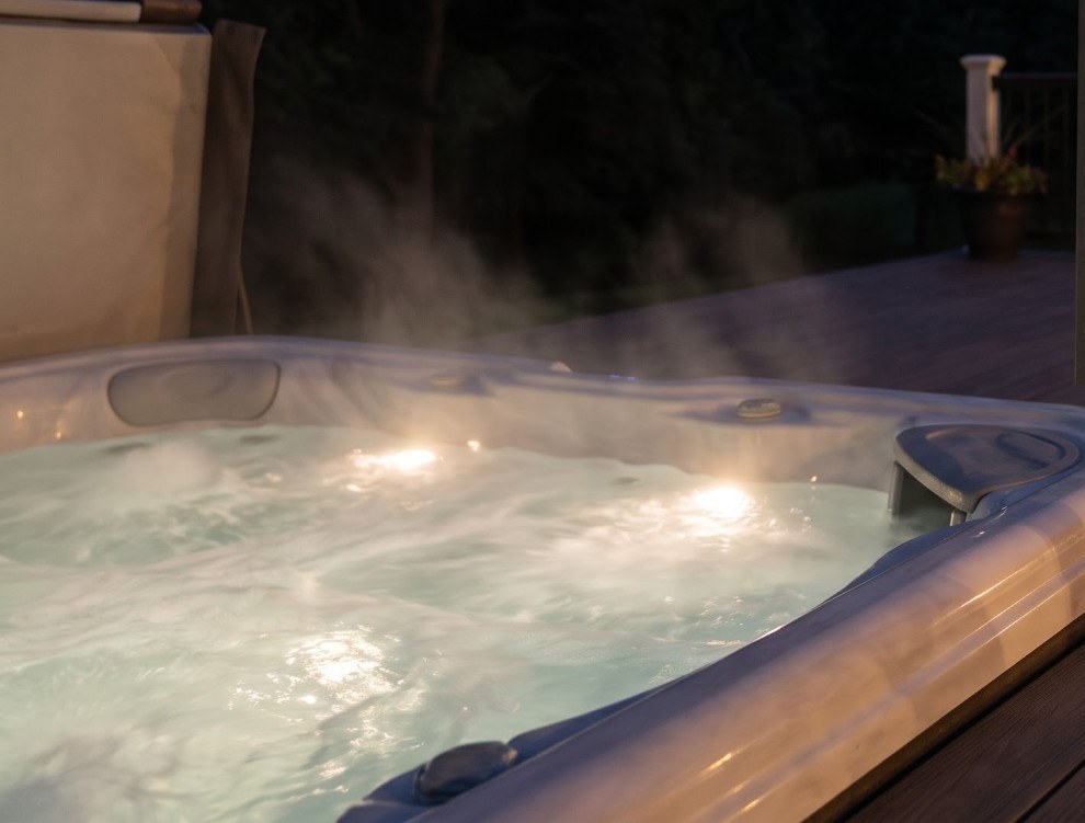 The seven-person Jacuzzi steaming on its deck at night, lit from within